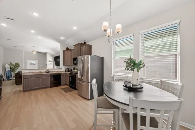 a kitchen with stainless steel appliances a dining table a potted plant and a window