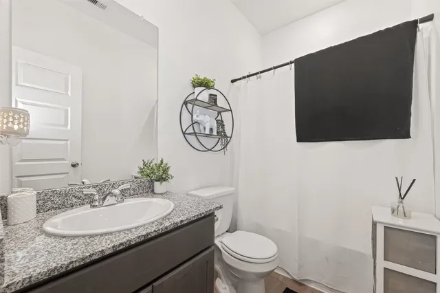 a bathroom with a granite countertop sink a toilet and a mirror