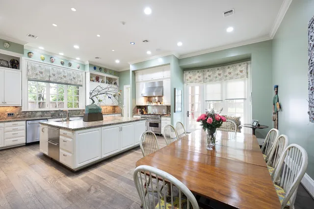 a kitchen with stainless steel appliances granite countertop a stove top oven a sink dishwasher kitchen island with chairs and wooden floor