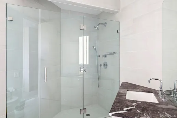 a bathroom with a granite countertop shower a sink and a mirror