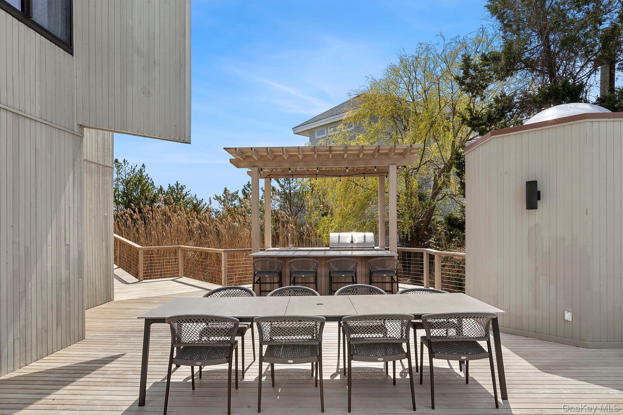 199 Dune Road Westhampton Beach, NY 11978 - Photo 25 of 38 a view of deck with table and chairs under an umbrella
