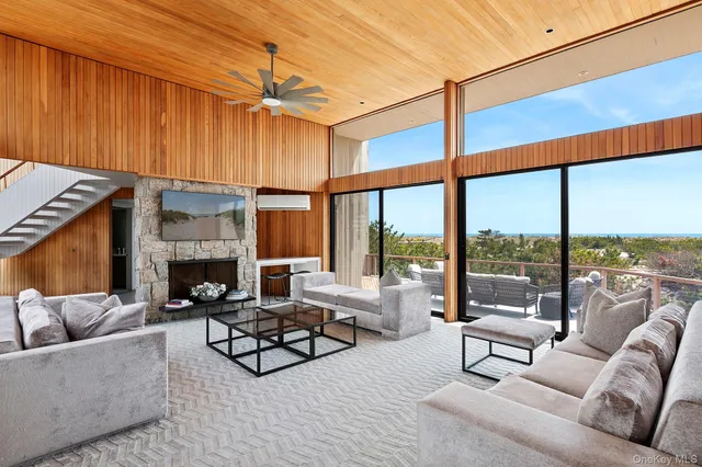 a living room with furniture a fireplace and a floor to ceiling window