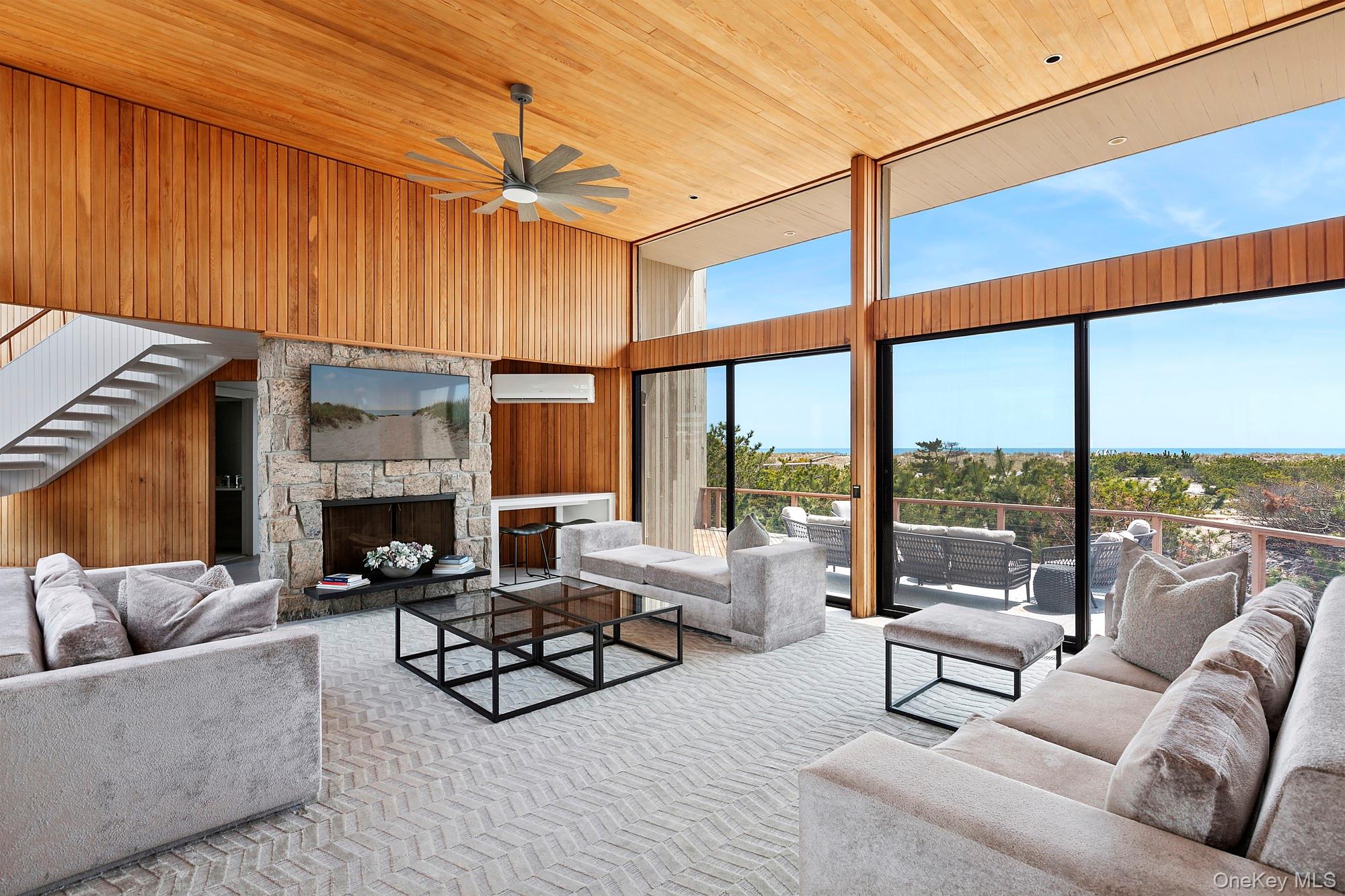 199 Dune Road Westhampton Beach, NY 11978 - Photo 7 of 38 a living room with furniture a fireplace and a floor to ceiling window