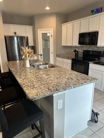 a kitchen with granite countertop white cabinets and a stove