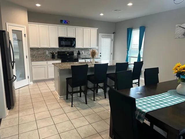 a open kitchen with stainless steel appliances granite countertop a stove a sink a dining table and chairs