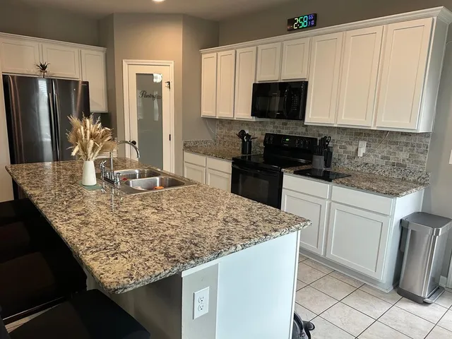 a kitchen with granite countertop white cabinets and stainless steel appliances