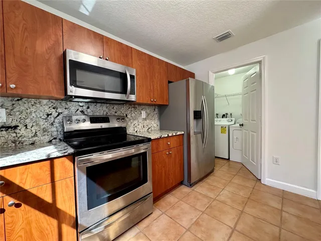 a kitchen with stainless steel appliances granite countertop a stove microwave and refrigerator