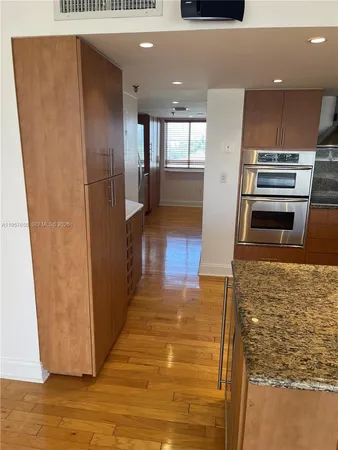 a view of a refrigerator in kitchen and an empty room
