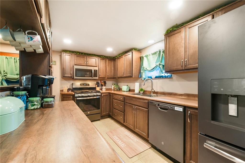 10 Bellview Drive McKees Rocks, PA 15136 - Photo 9 of 25 a kitchen with stainless steel appliances granite countertop a refrigerator a sink dishwasher a stove top oven a dining table and chairs with wooden floor