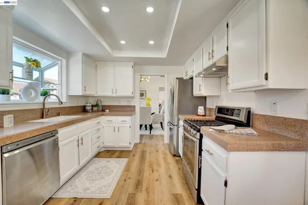 a kitchen with white cabinets appliances and a window