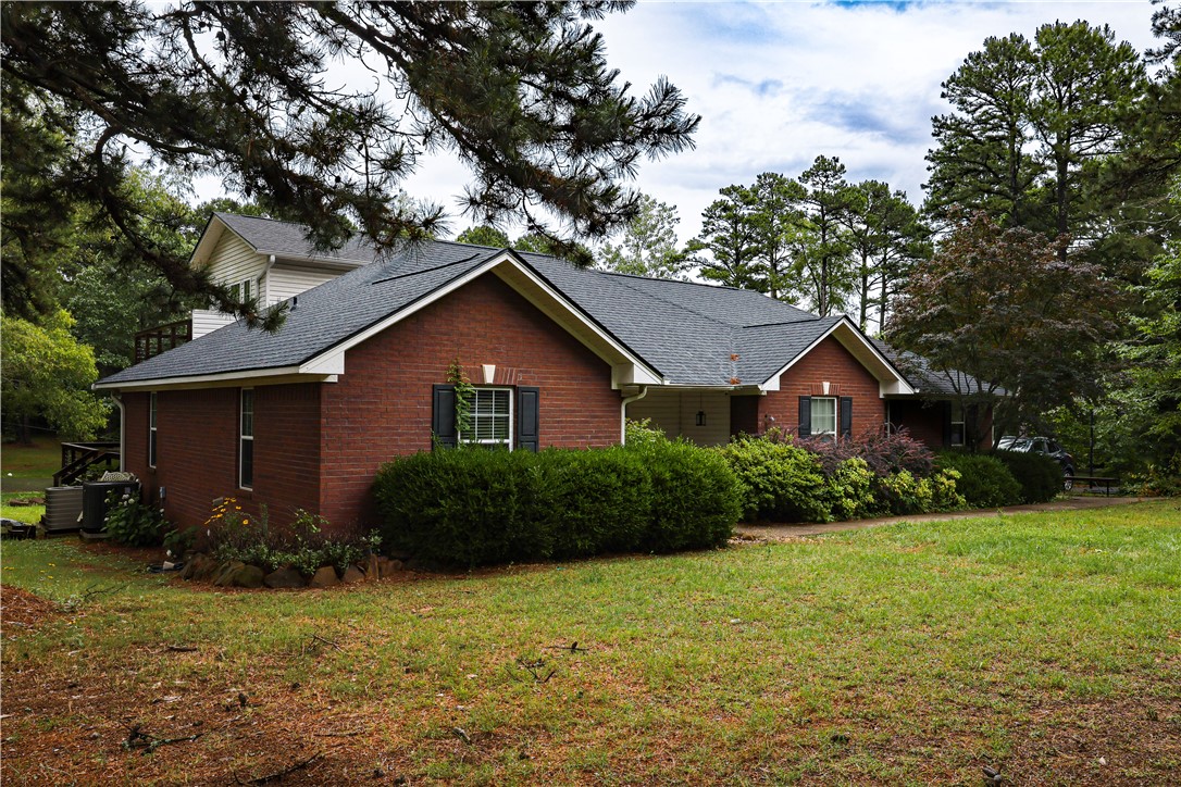 164 Park Road Russellville, AR 72802 - Photo 30 of 35 Brick exterior home featuring a dark shingle roof, established landscaping, and mature trees
