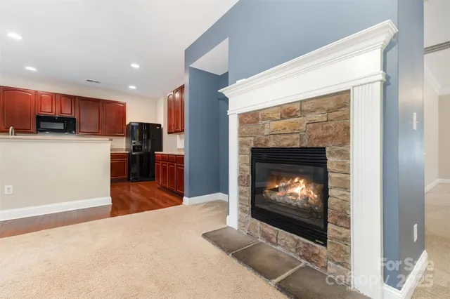 a living room with stainless steel appliances furniture a fireplace a flat screen tv and a fireplace