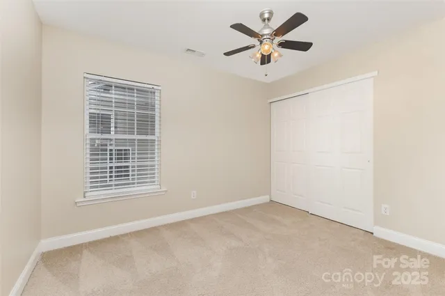 an empty room with window and ceiling fan