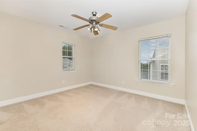 an empty room with ceiling fan and window