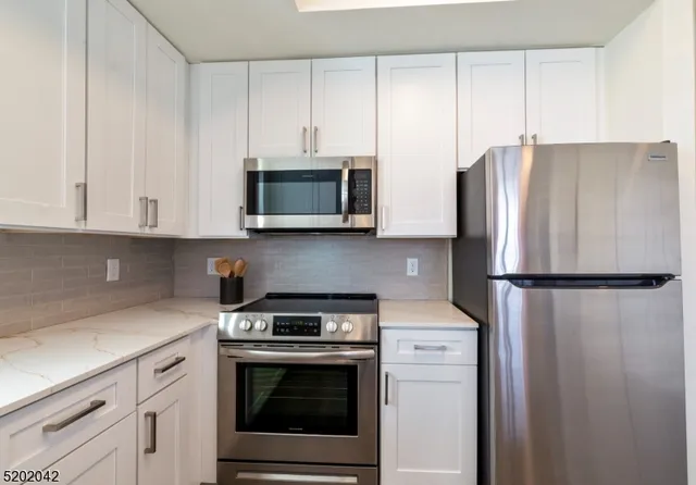 a kitchen with stainless steel appliances white cabinets white stove a microwave and a refrigerator