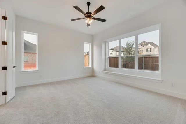 an empty room with windows and ceiling fan