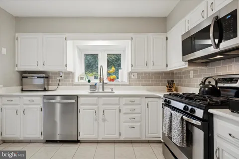 a kitchen with stainless steel appliances granite countertop grey cabinets a stove a sink and dishwasher