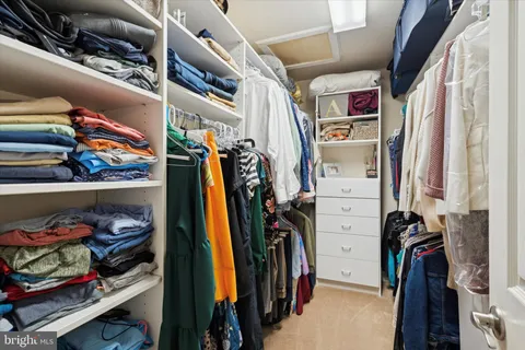 a view of walk in closet with clothes and shoes