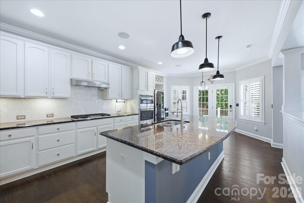 1825 Laveta Road Charlotte, NC 28269 - Photo 13 of 48 a kitchen with granite countertop stainless steel appliances a table chairs in it and white cabinets