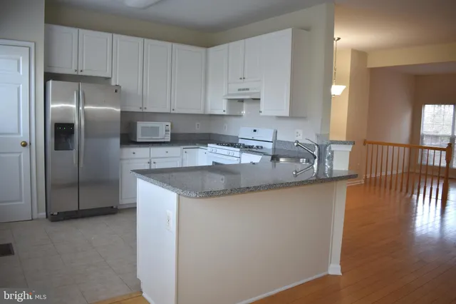 a kitchen with stainless steel appliances granite countertop a sink a refrigerator and a granite counter tops