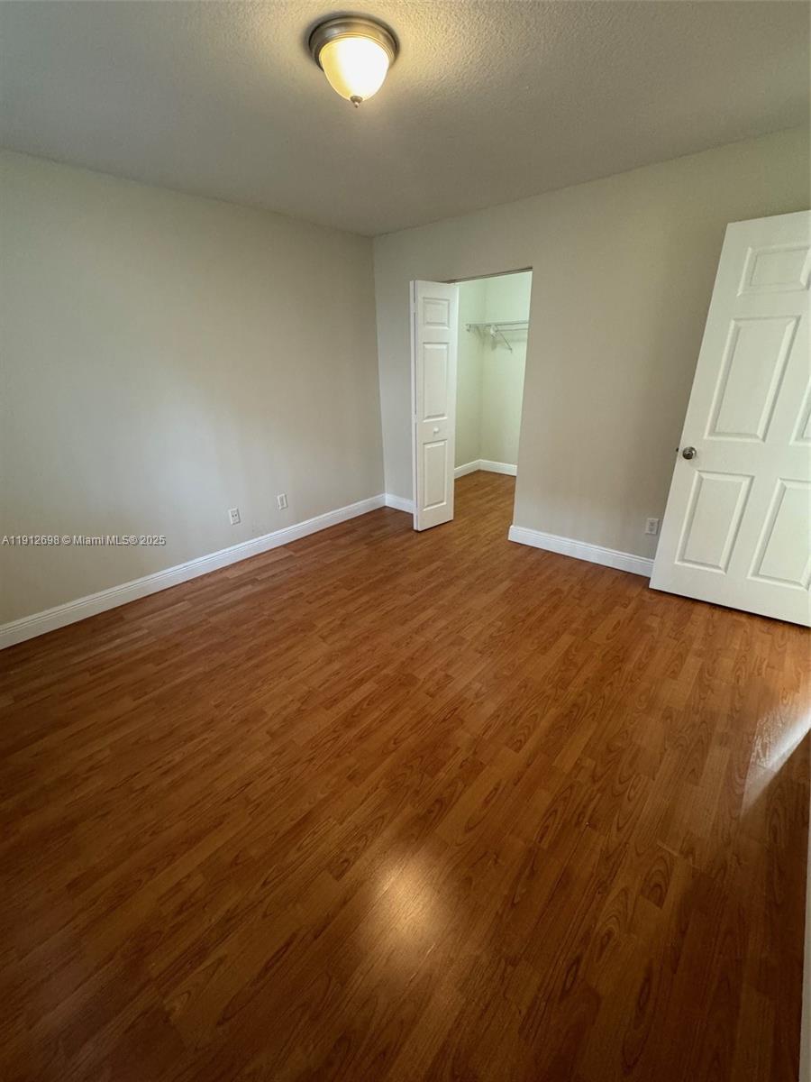 4025 West McNab Road, Unit E109 Pompano Beach, FL 33069 - Photo 12 of 13 an empty room with wooden floor and windows