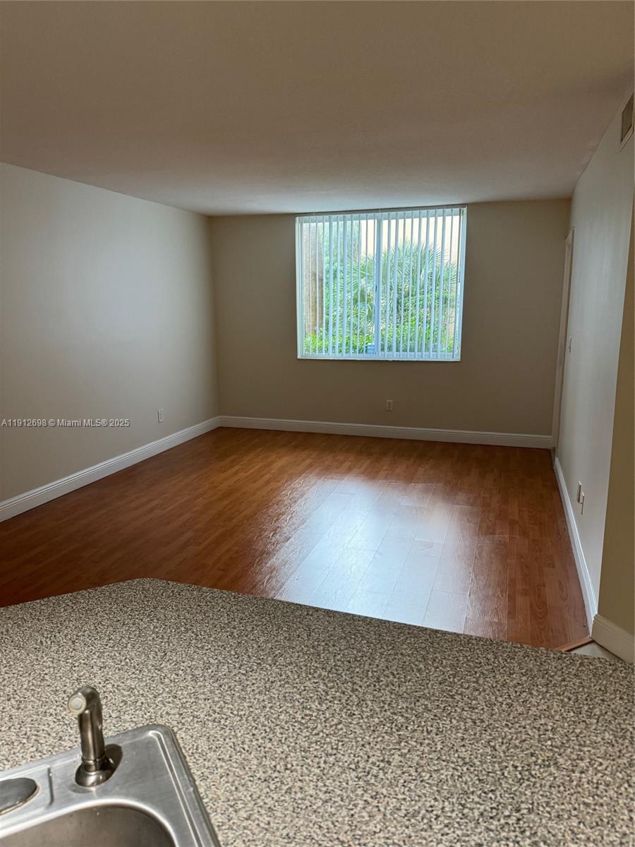 4025 West McNab Road, Unit E109 Pompano Beach, FL 33069 - Photo 4 of 13 an empty room with wooden floor and windows