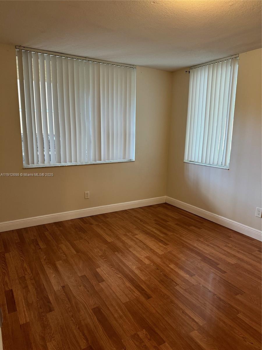 4025 West McNab Road, Unit E109 Pompano Beach, FL 33069 - Photo 10 of 13 a view of an empty room with wooden floor and a window