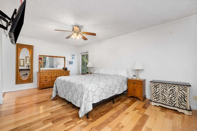 a bedroom with a large bed a flat tv screen and a ceiling fan