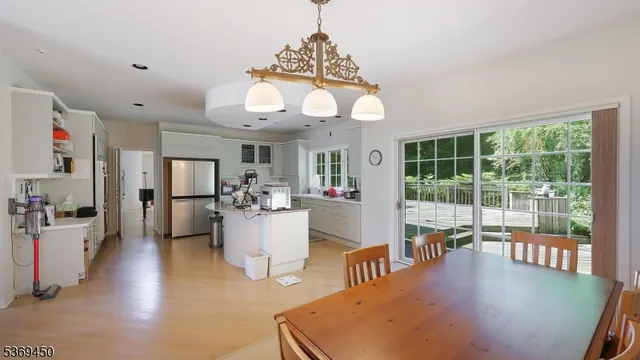 a dining room with wooden floor a chandelier a wooden table and chairs