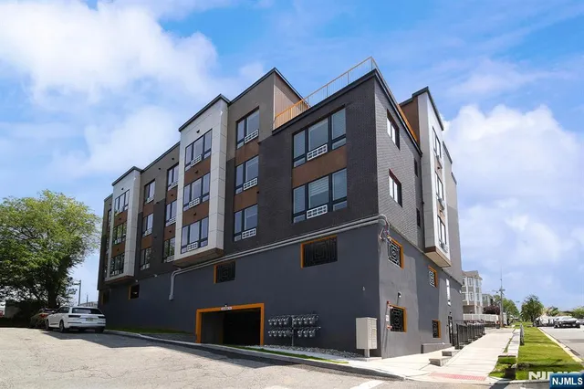 a front view of a building with lot of cars and trees