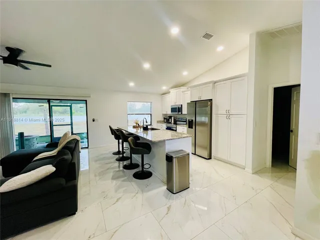 a kitchen with stainless steel appliances kitchen island granite countertop a refrigerator and a sink