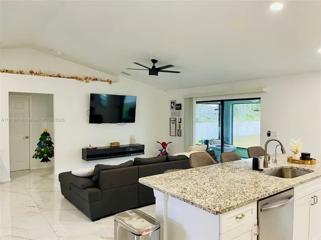 a living room with furniture kitchen view and a flat screen tv