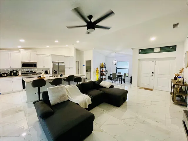 a living room with furniture kitchen view and a window