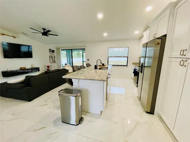 a living room with furniture and a refrigerator