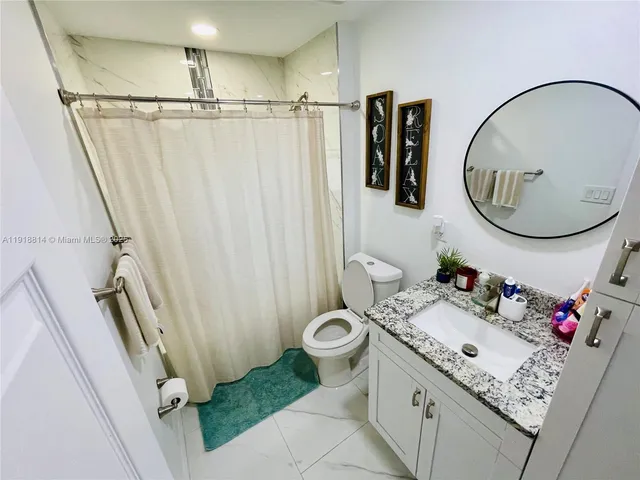 a bathroom with a granite countertop sink mirror vanity and toilet