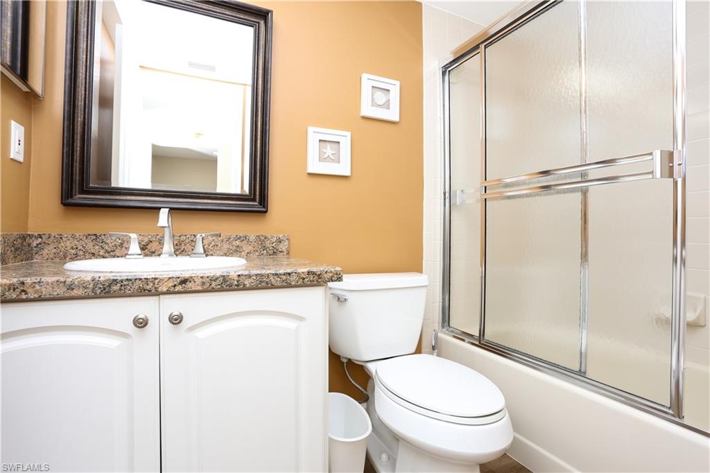 5908 Cranbrook Way, Unit I103 Naples, FL 34112 - Photo 7 of 26 a bathroom with a granite countertop toilet sink and a mirror