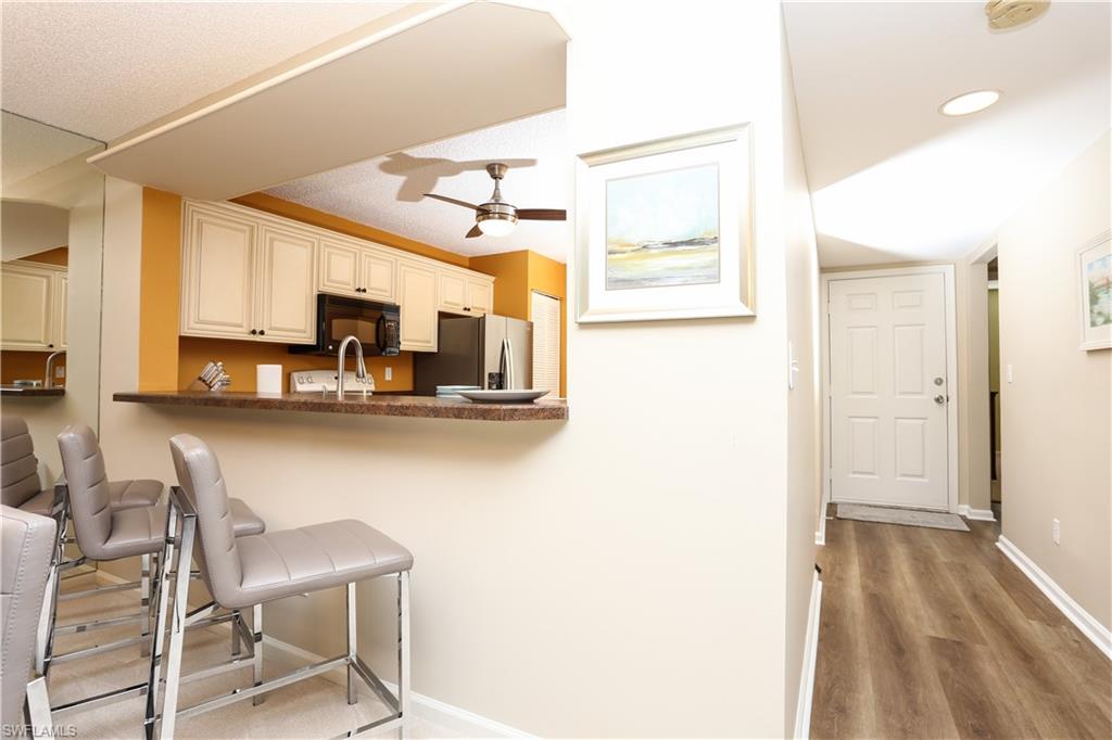 5908 Cranbrook Way, Unit I103 Naples, FL 34112 - Photo 8 of 26 a kitchen with stainless steel appliances kitchen island granite countertop a refrigerator and microwave