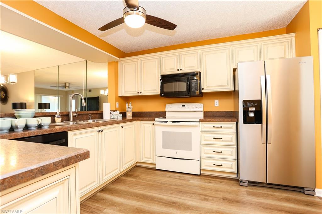 5908 Cranbrook Way, Unit I103 Naples, FL 34112 - Photo 9 of 26 a kitchen with stainless steel appliances a stove microwave and refrigerator