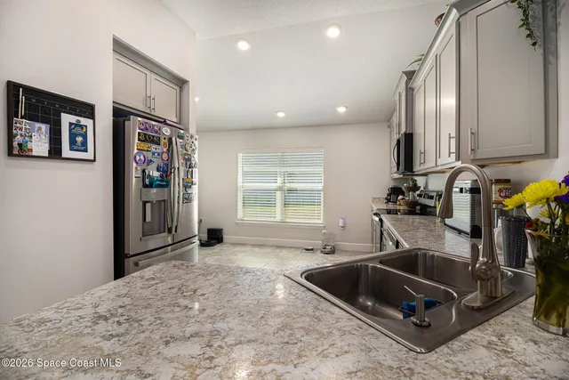 a kitchen with stainless steel appliances granite countertop a sink and a refrigerator