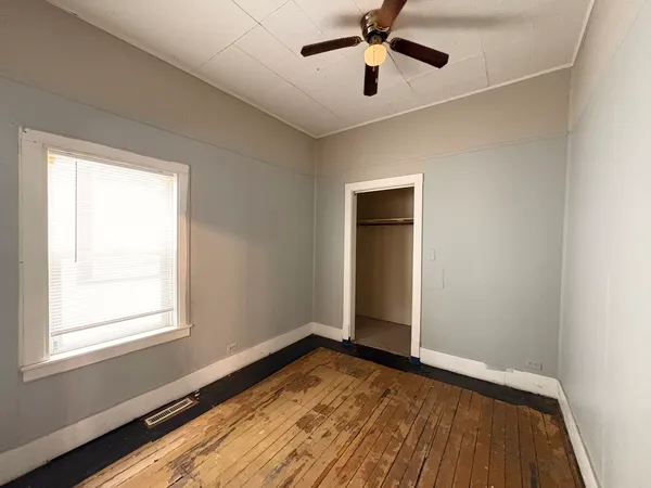 a view of empty room with wooden floor and fan