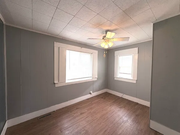 a view of an empty room with a window and wooden floor