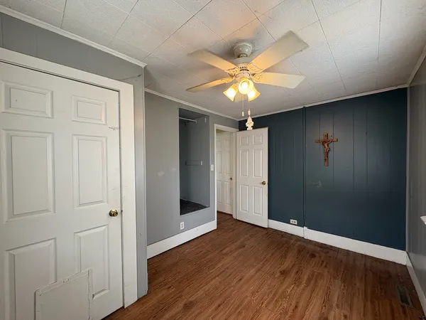 an empty room with wooden floor closet and windows