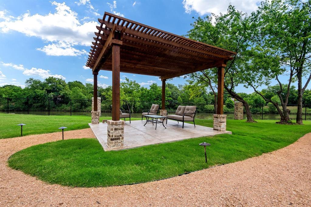 770 North Plano Road, Unit 303 Richardson, TX 75081 - Photo 23 of 26 Outdoor living area featuring a wooden pergola with stone-clad pillars, a paved patio, and a gravel path