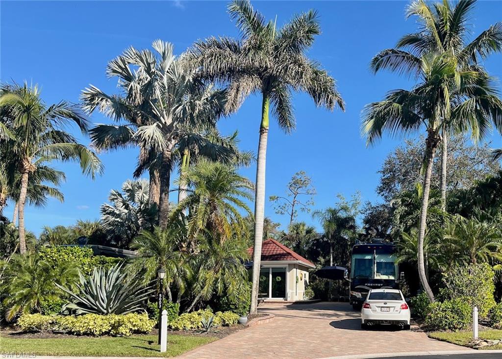 5003 Coach Lane Naples, FL 34114 - Photo 2 of 17 a car parked in front of a house with a palm tree