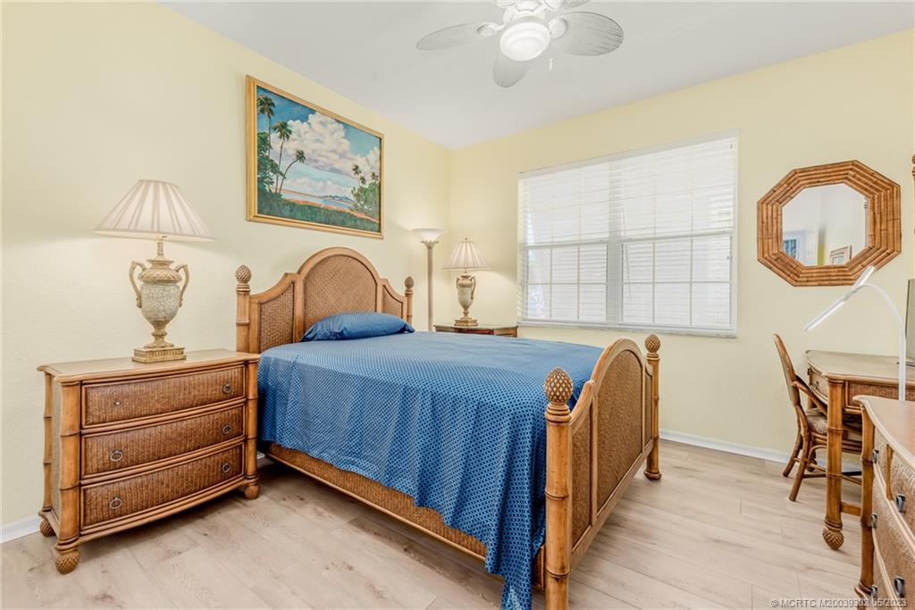 2032 Northwest Marsh Rabbit Lane Stuart, FL 34994 - Photo 25 of 30 a bedroom with a bed and a chandelier