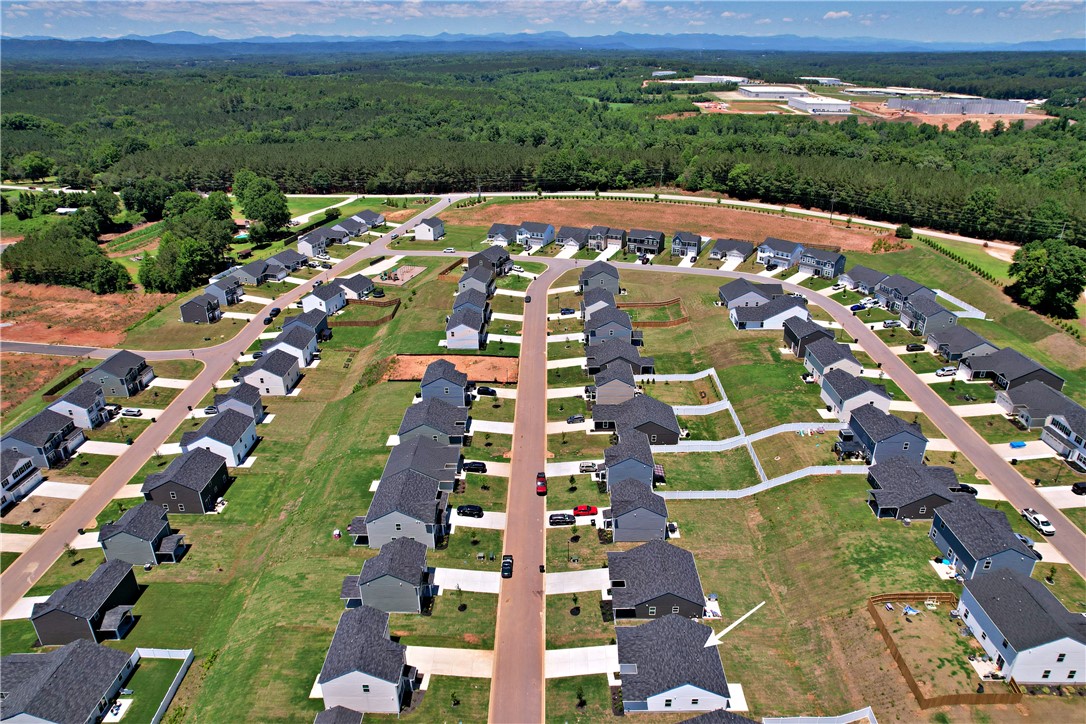 723 Peridot Way Westminster, SC 29693 - Photo 38 of 45 An aerial perspective showcases a vibrant, developing residential neighborhood nestled against a backdrop of lush forests and distant mountains.