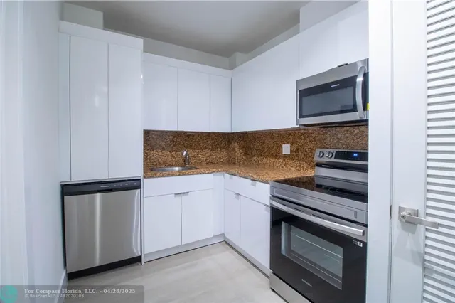 a kitchen with granite countertop white cabinets and stainless steel appliances