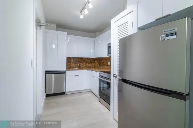 a kitchen with a refrigerator and white cabinets