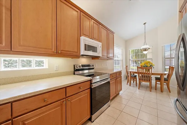 a kitchen with stainless steel appliances granite countertop a stove a sink a dining table and chairs with wooden floor