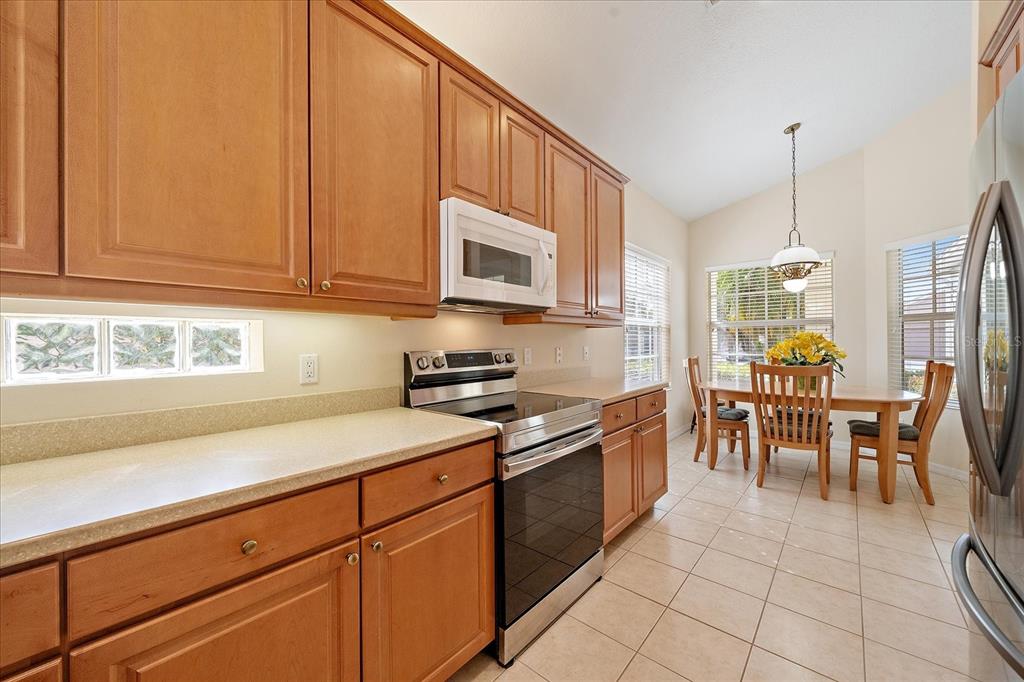 6476 Rookery Circle Bradenton, FL 34203 - Photo 6 of 44 a kitchen with stainless steel appliances granite countertop a stove a sink a dining table and chairs with wooden floor